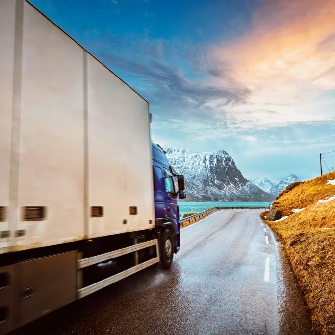 Truck on road in Norwegian fjord on sunset. Lofoten islands, Norway. Motion blur